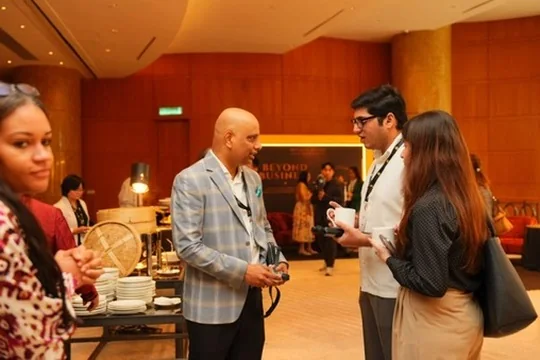 Guests talking between sessions at the ACES Summit 2026 in front of the Beyond Business theme wall