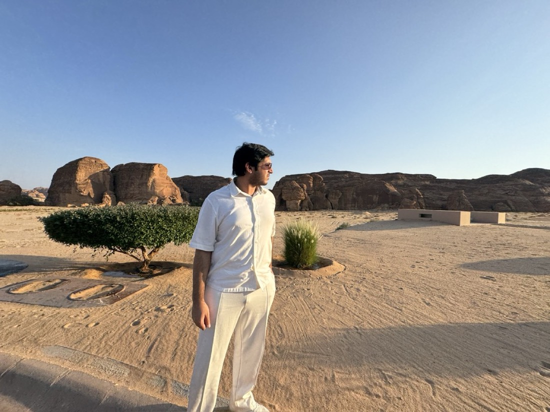 Husnain in white standing in a desert with sandstone rock formations