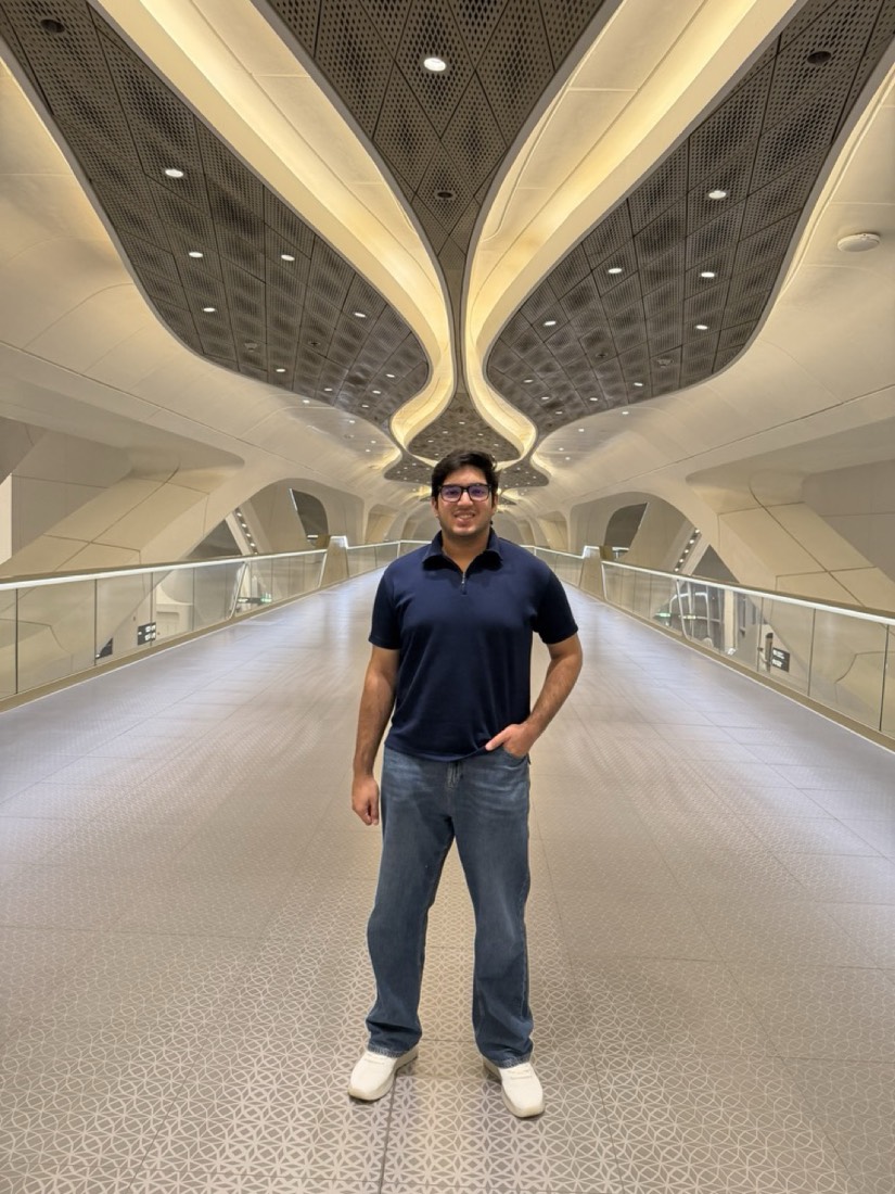 Husnain on a futuristic white walkway with a sculpted ceiling